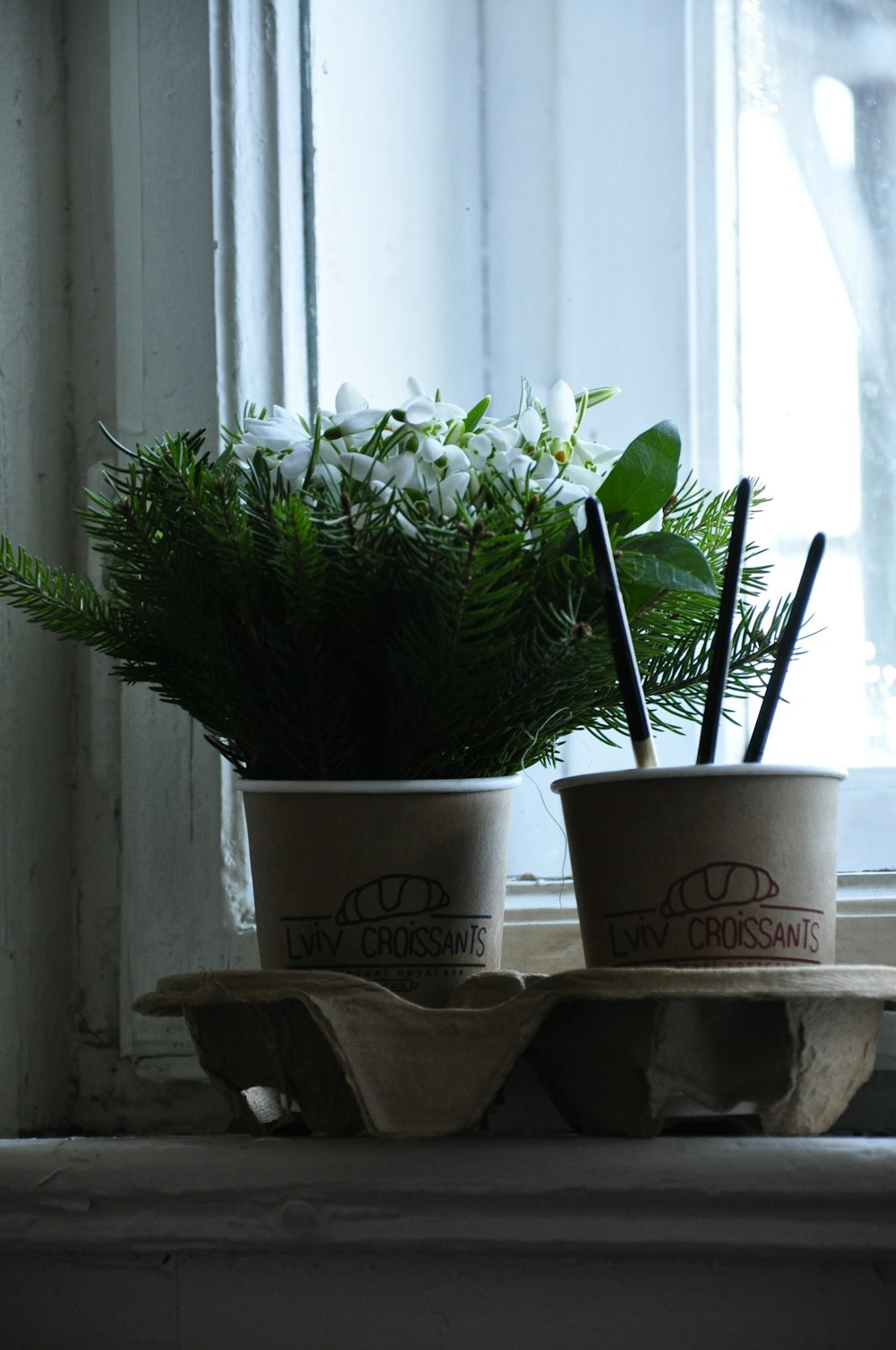 a couple of cups sitting on top of a window sill