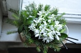 A cozy scene with a bouquet of mixed seasonal flowers on a windowsill dusted with snow.
