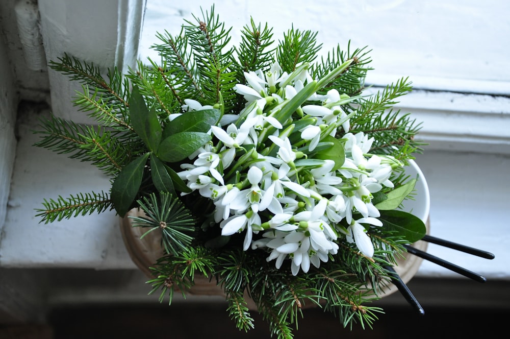 a bouquet of white flowers sitting on top of a window sill