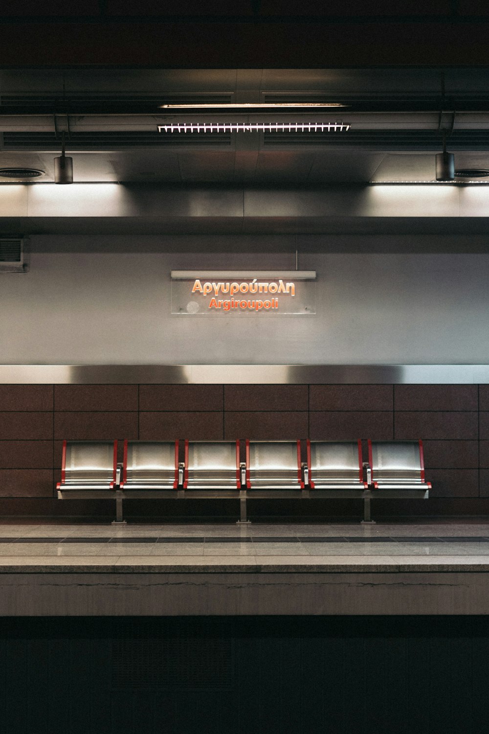 a train station with benches and a sign on the wall