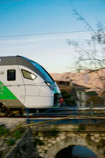 A sleek modern train gliding along tracks through a scenic countryside.