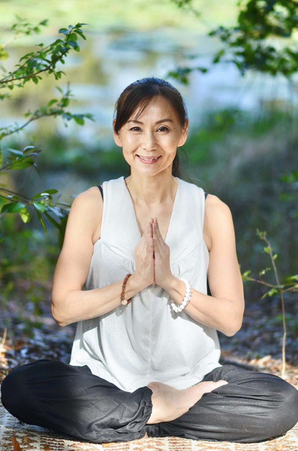 a woman in a white shirt and black pants sitting in a yoga pose