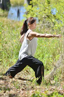 a woman in a white shirt and black pants doing a yoga pose