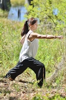 a woman in a white shirt and black pants doing a yoga pose