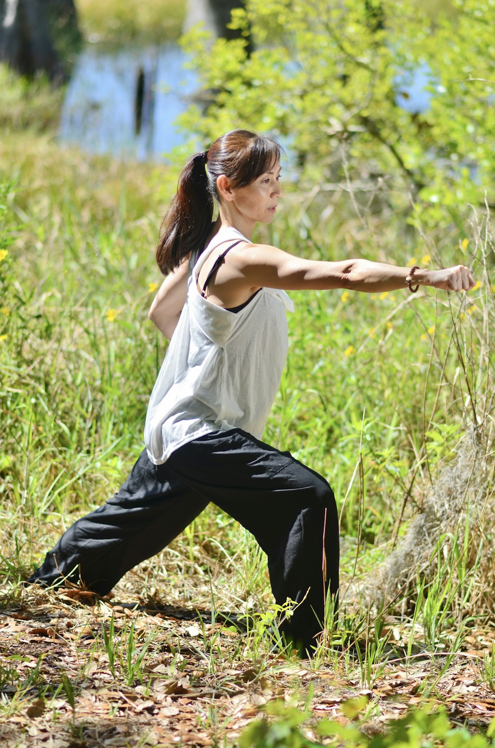 a woman in a white shirt and black pants doing a yoga pose