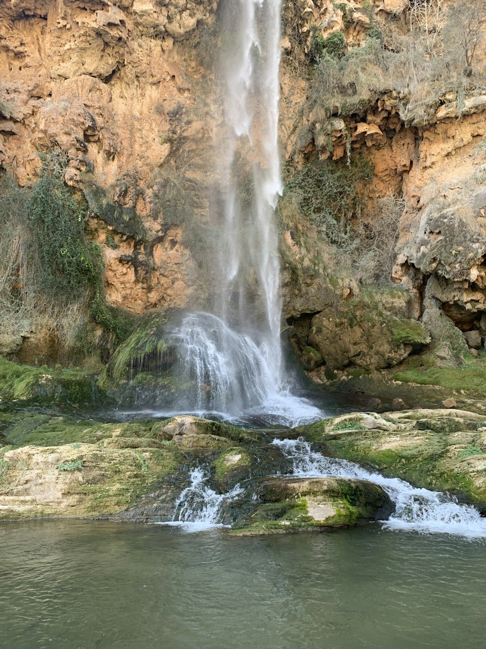 a waterfall with a man standing in front of it