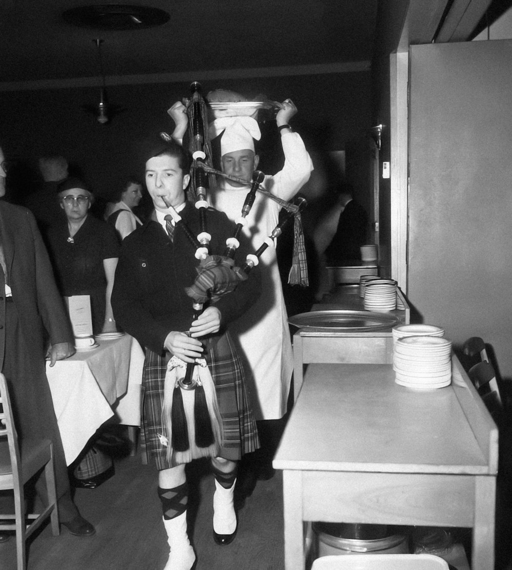 a man in a kilt walking through a room