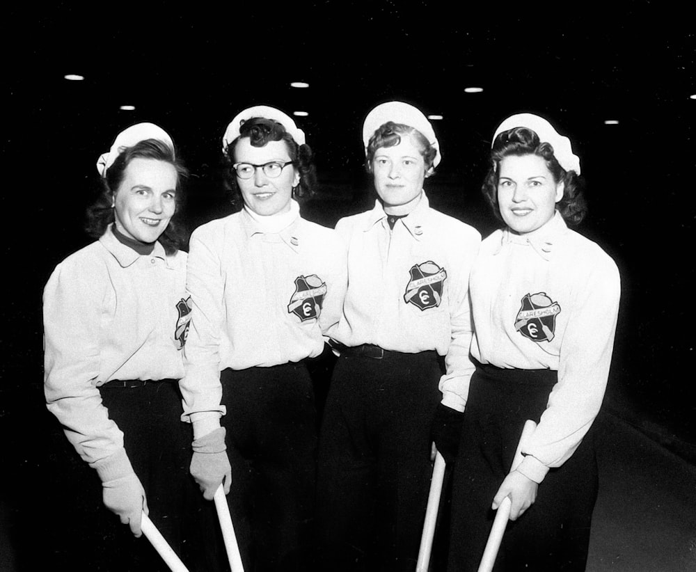 Un grupo de mujeres de pie una al lado de la otra sosteniendo bates de béisbol