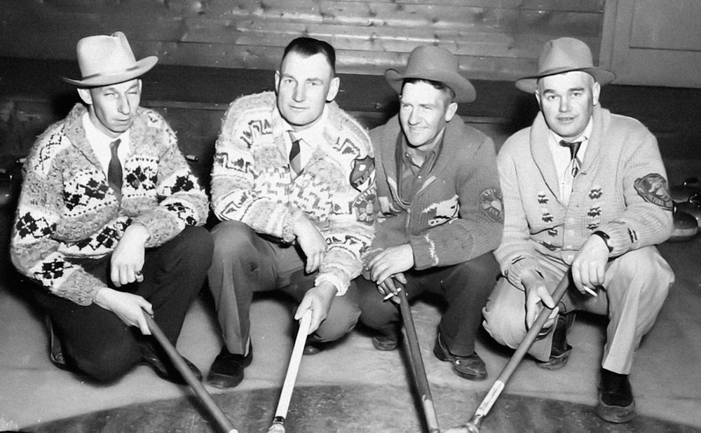 a group of men sitting next to each other holding baseball bats