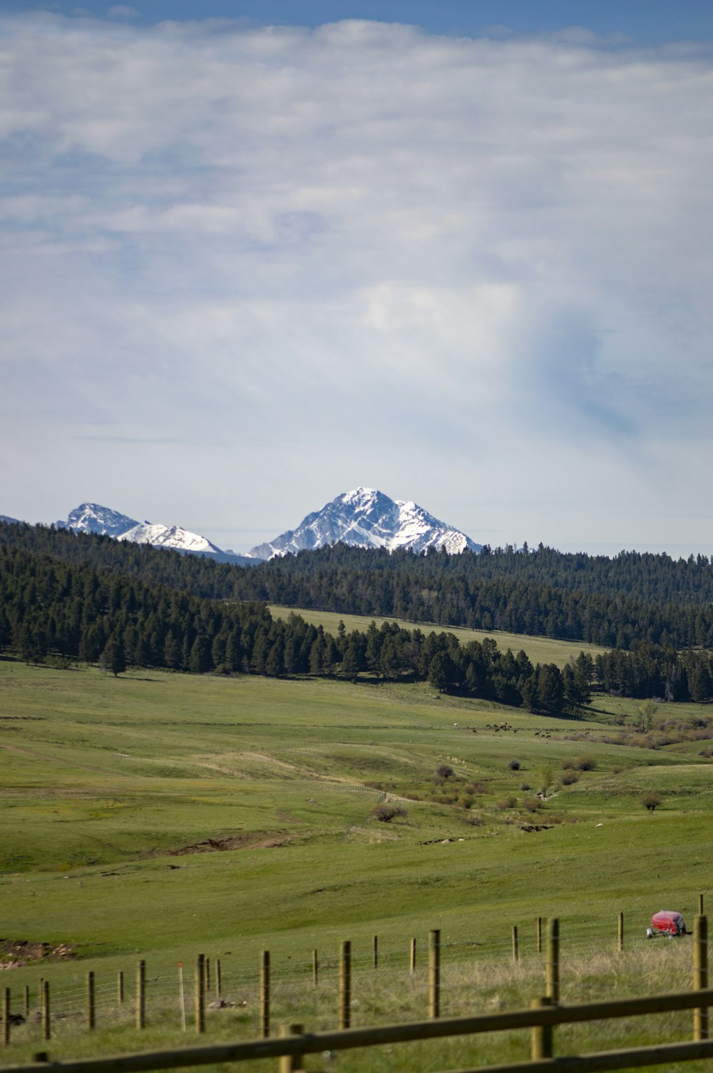 a field with a fence and mountains in the background