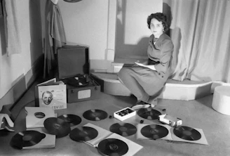 a woman sitting on the floor surrounded by records