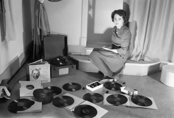 a woman sitting on the floor surrounded by records
