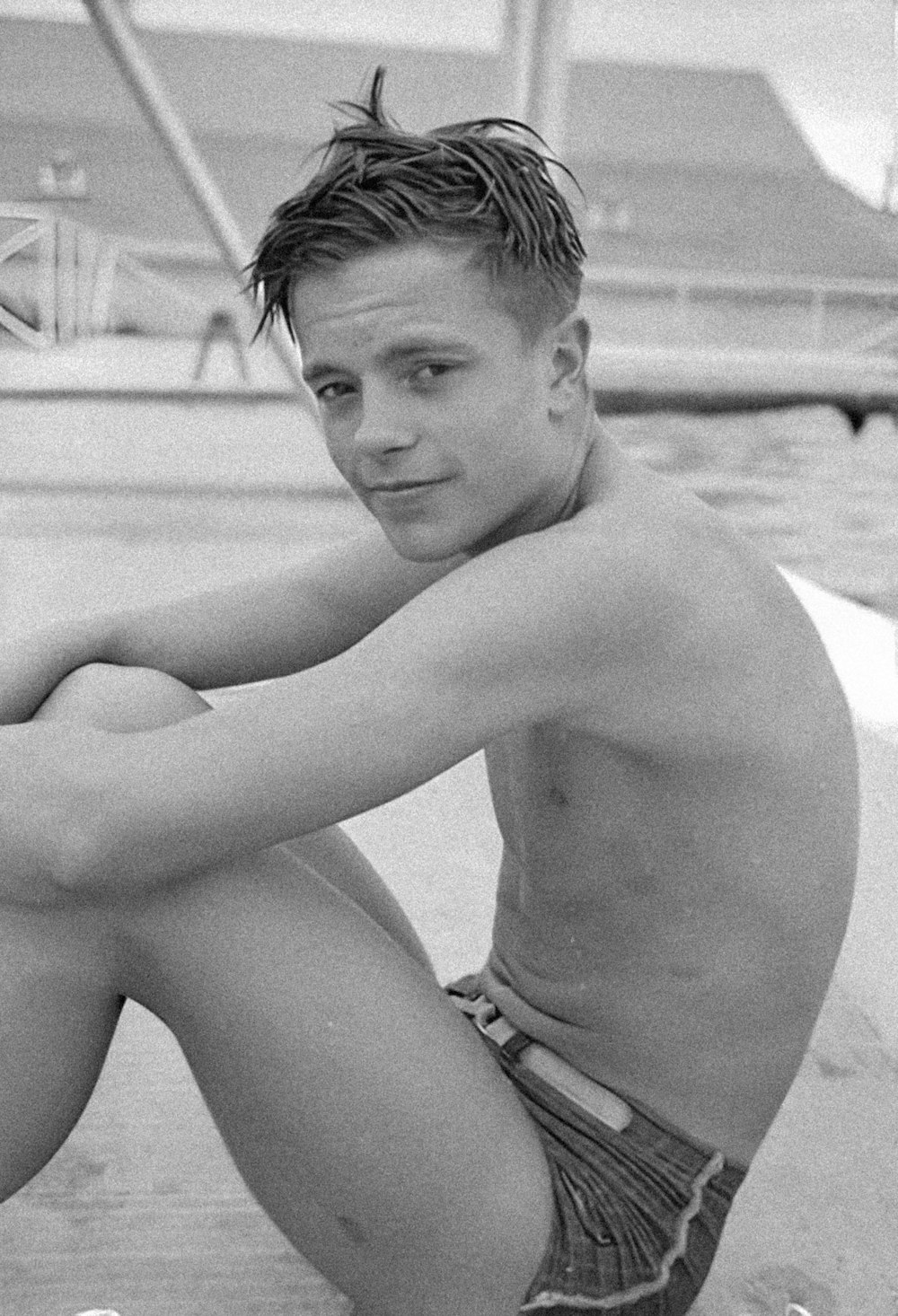 a man sitting on the side of a swimming pool