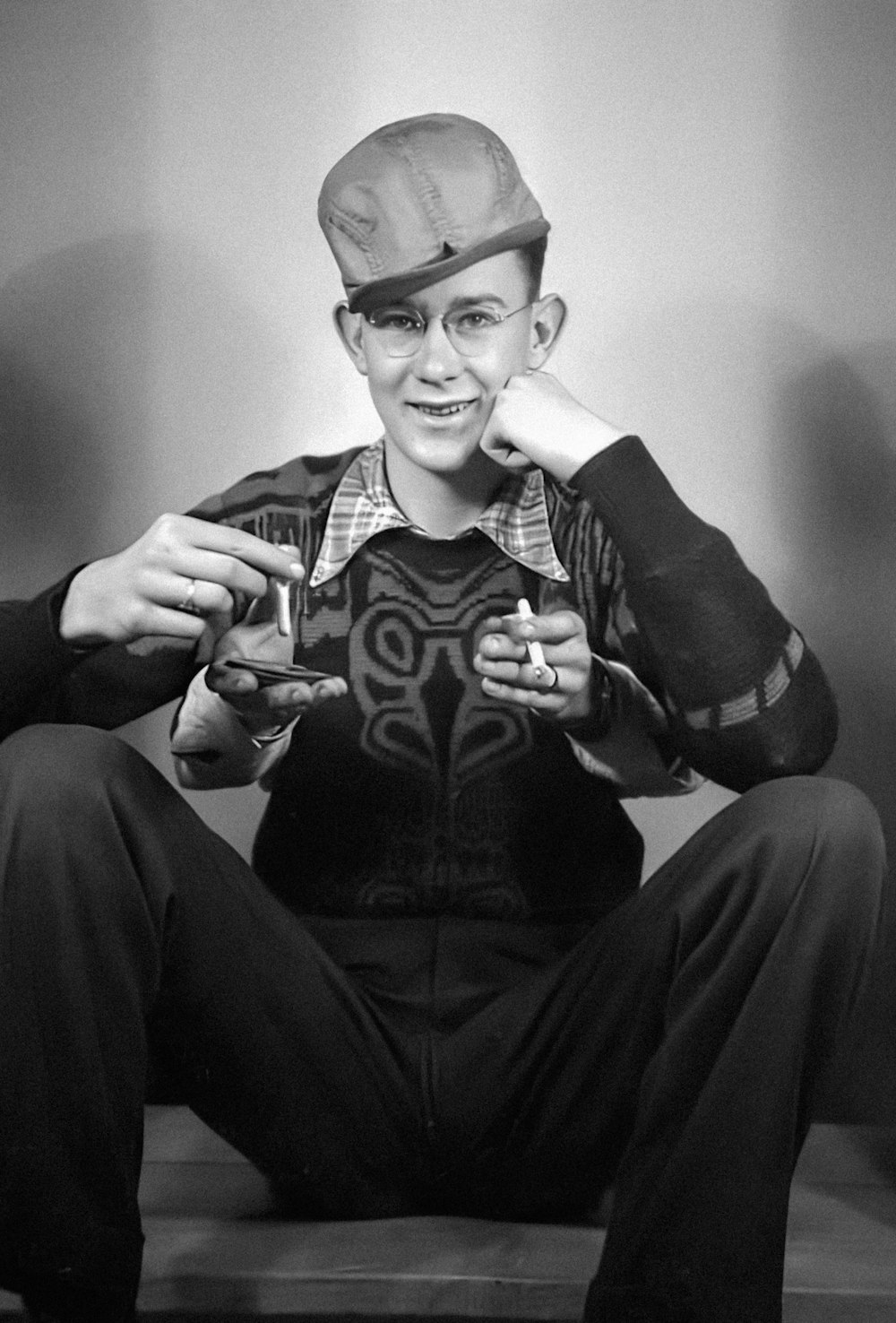 a man sitting on the floor holding a pair of scissors