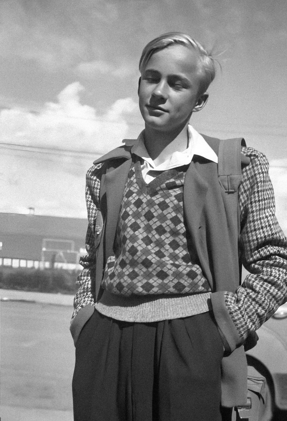 a black and white photo of a man standing in front of a car