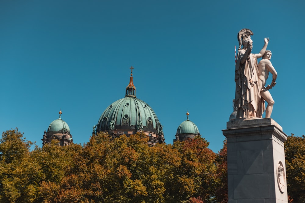 a statue stands in front of a domed building