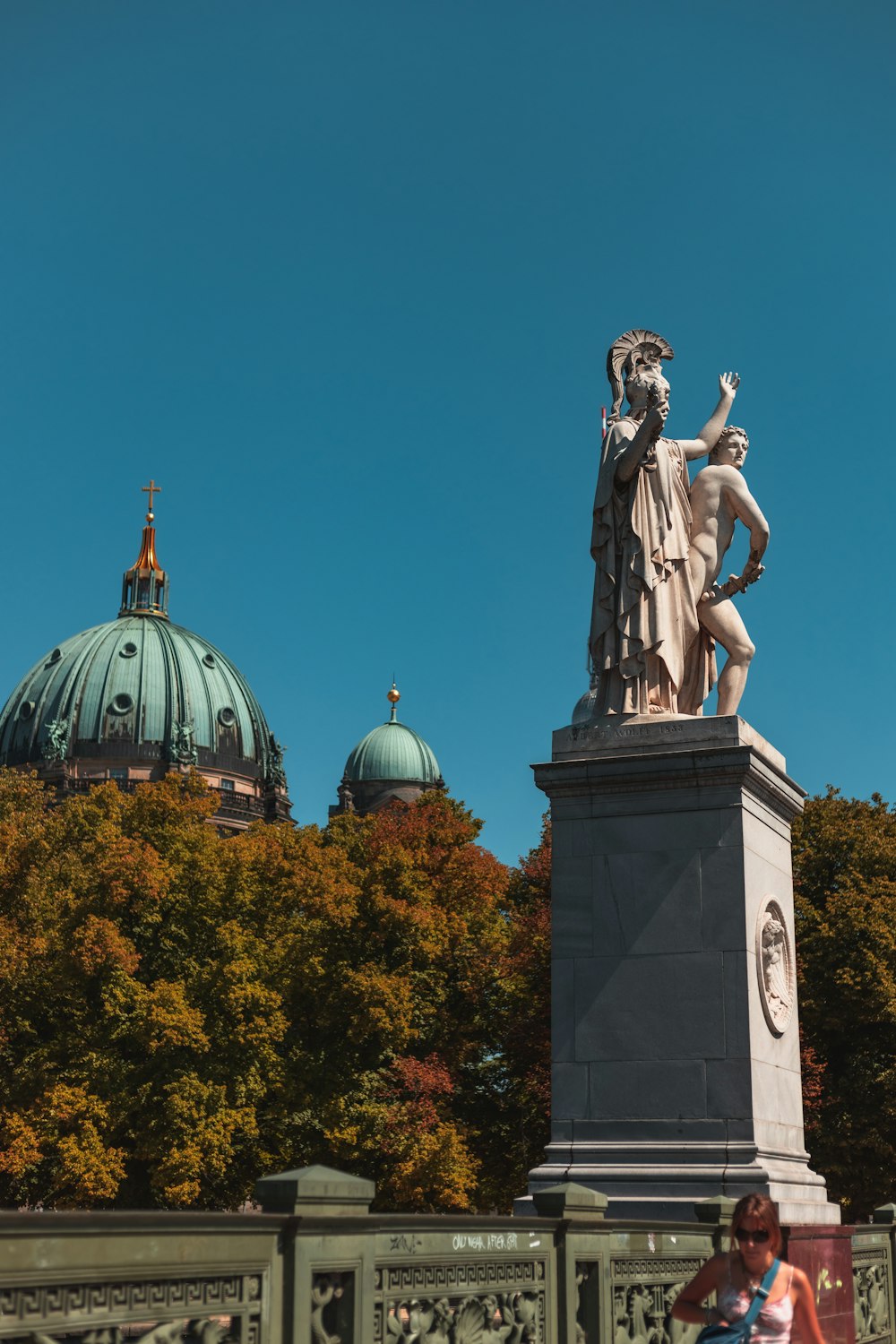 a statue of a woman holding a bird on top of a bridge