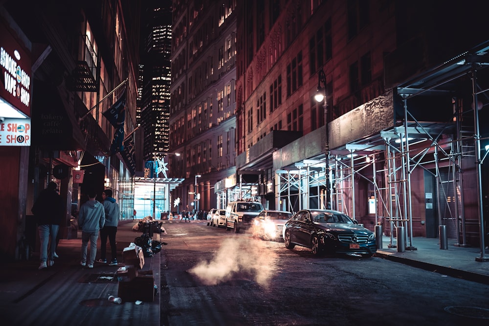 a city street at night with cars parked on the side of the street