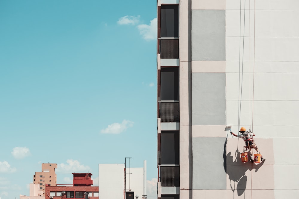 a man on a ladder painting the side of a building
