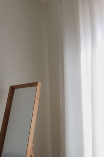 a mirror sitting next to a window in a room