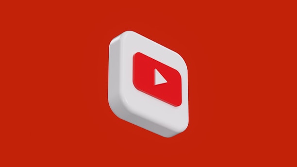 A three-dimensional representation of a white square icon with rounded edges featuring a red play button in the center is set against a solid red background.