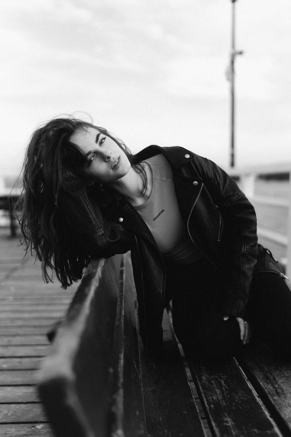 a black and white photo of a woman leaning on a bench