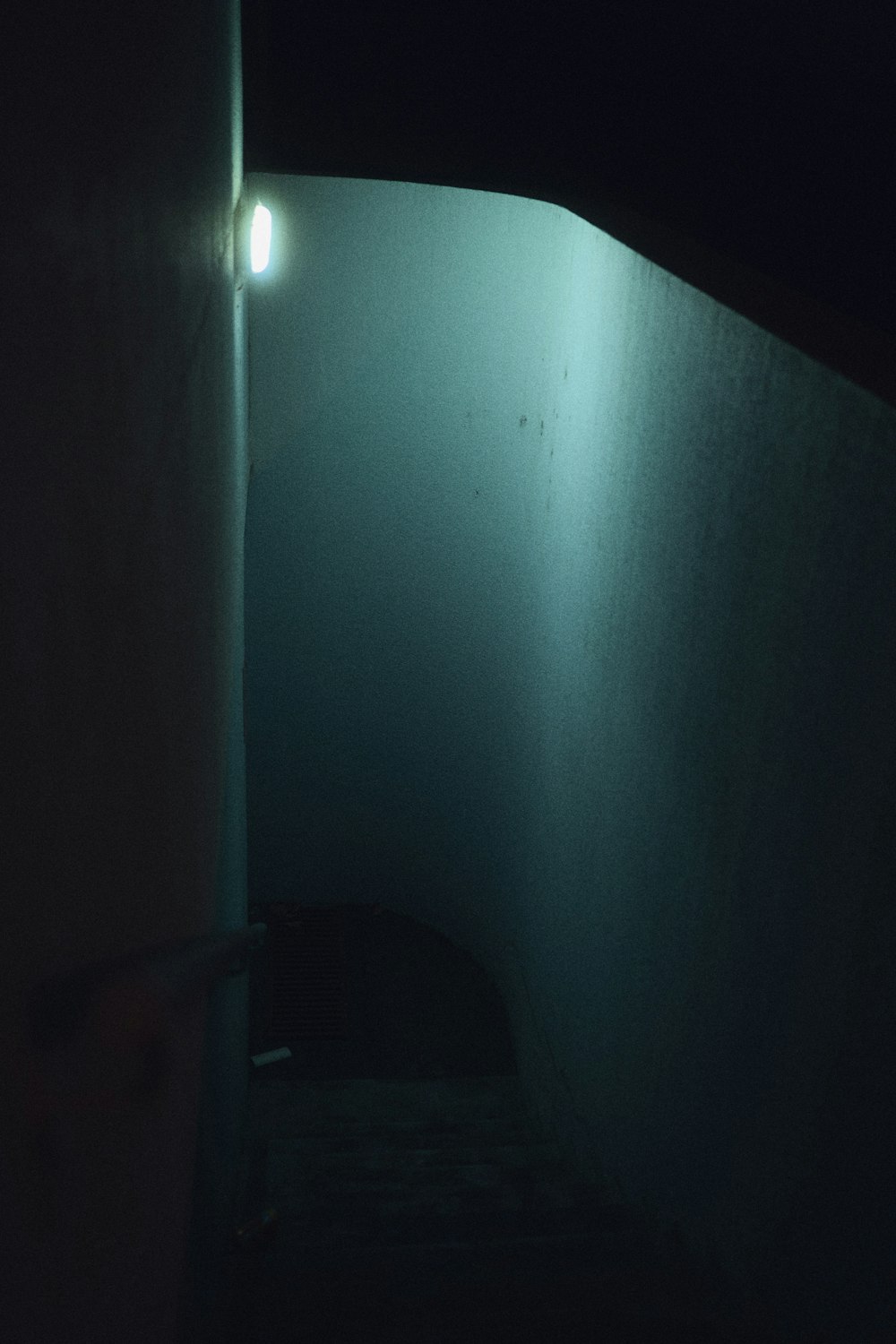 a dark hallway with a light shining in the corner