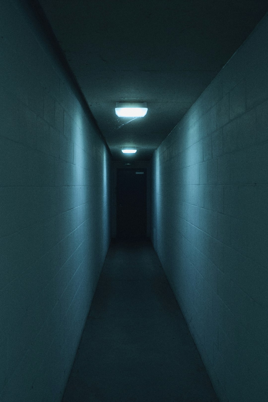 a long dark hallway with a light at the end