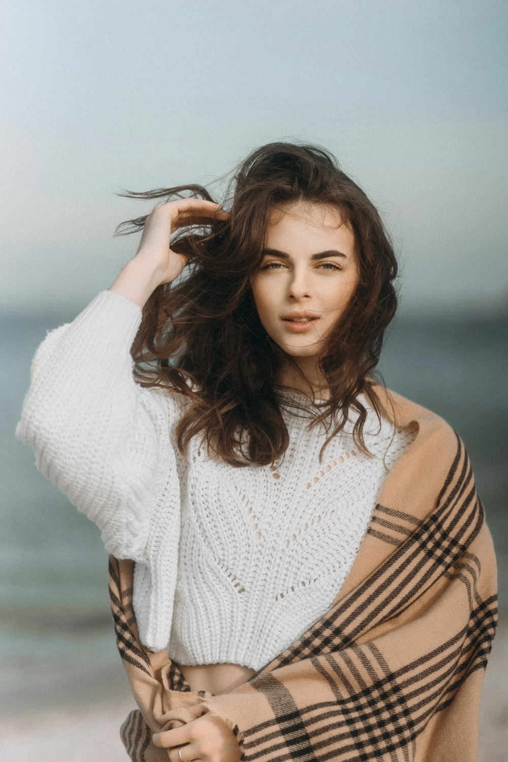 a woman standing on top of a beach covered in a blanket