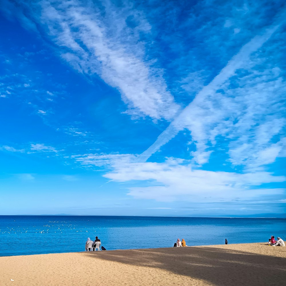 a group of people sitting on top of a sandy beach