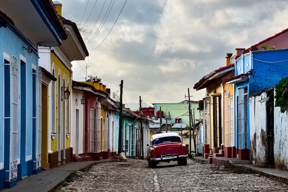 a red car is parked on a cobblestone street