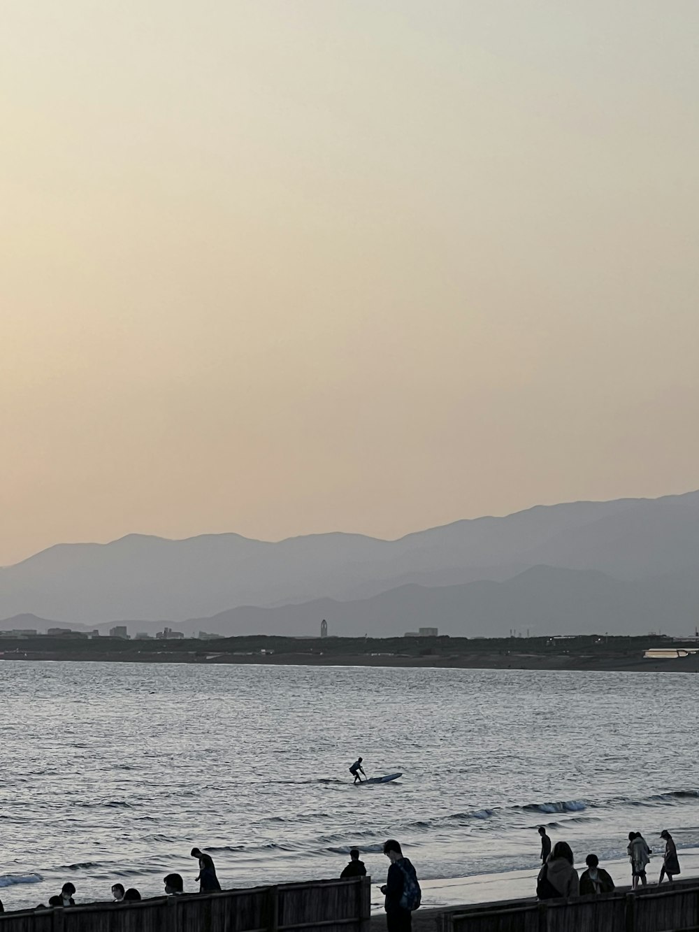 a group of people standing on top of a beach next to the ocean