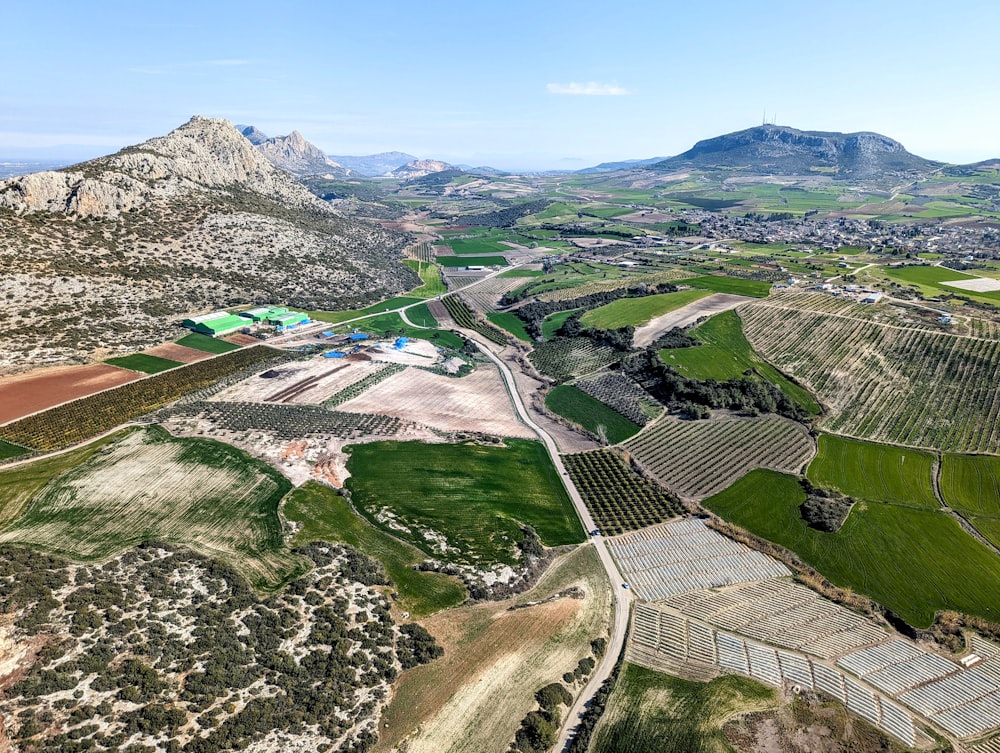 an aerial view of a farm land with mountains in the background