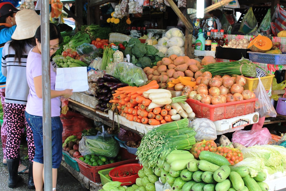 a woman standing in front of a fruit and vegetable stand