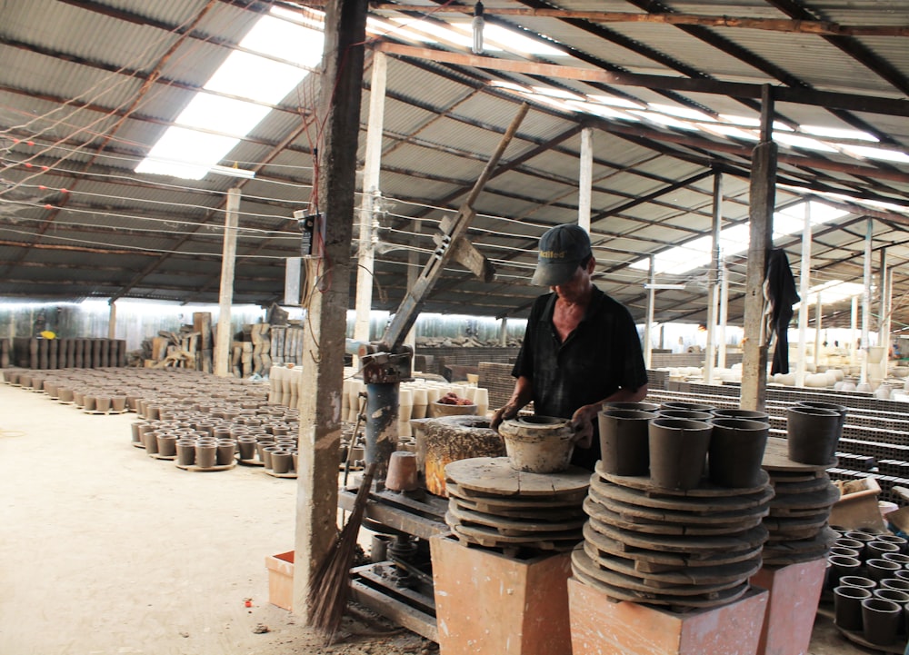 Un hombre trabajando en una fábrica con muchas ollas