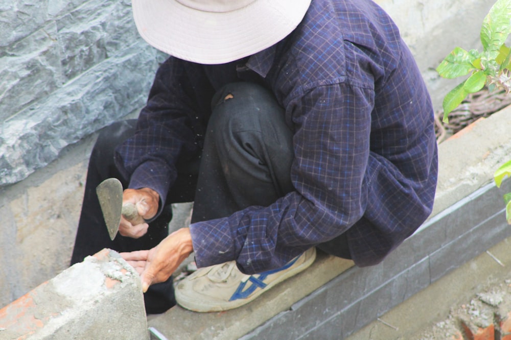 a man sitting on a ledge working on something