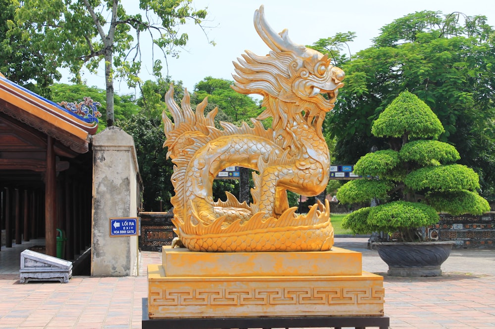 Una statua di drago dorato in un ambiente del parco