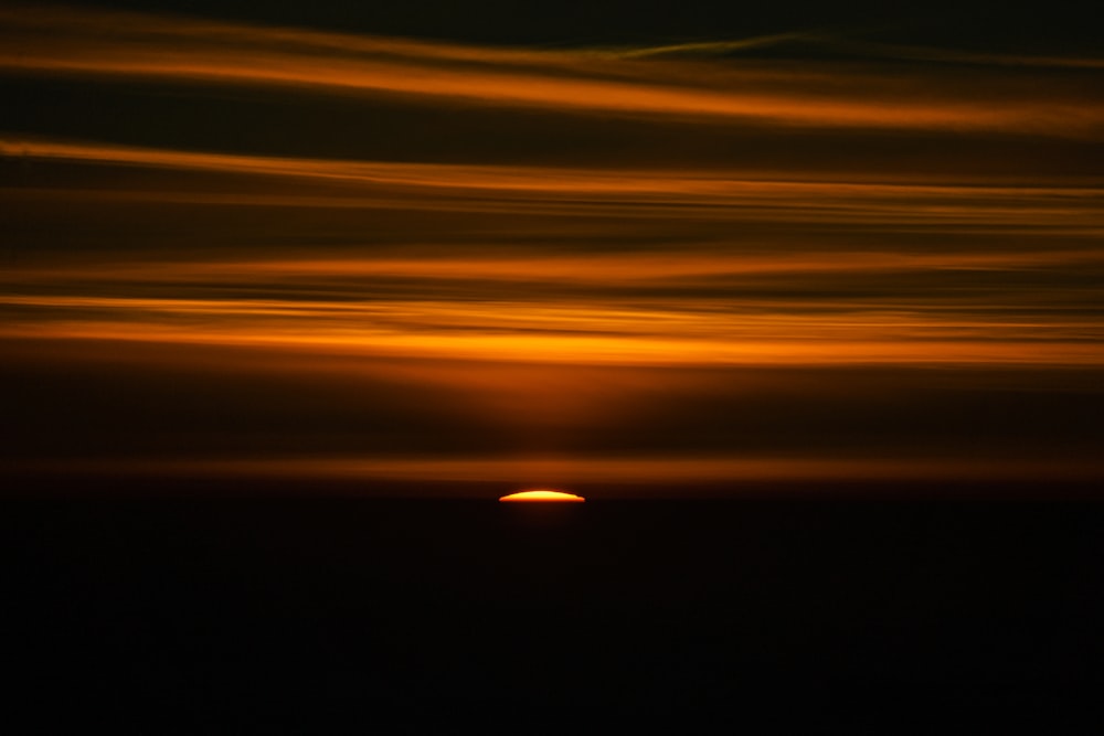 the sun is setting over the horizon of the ocean