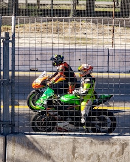 two people on a motorcycle behind a fence