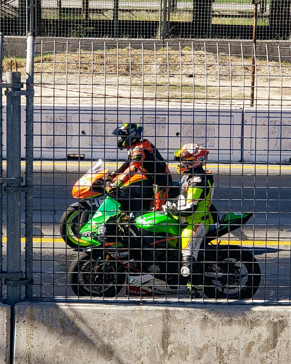 two people on a motorcycle behind a fence