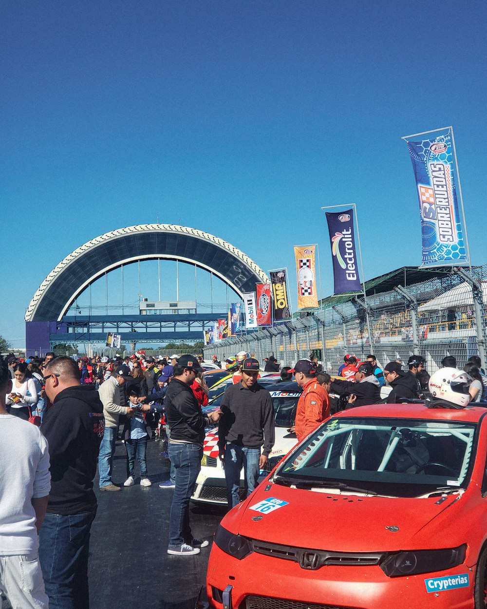 a group of people standing around a red car