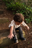 a young boy sitting on a log in the woods