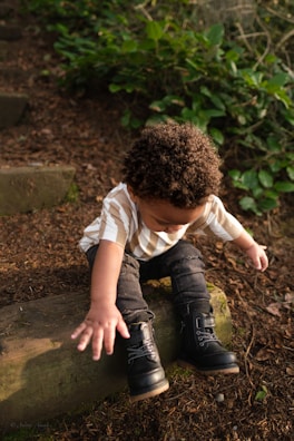 a young boy sitting on a log in the woods