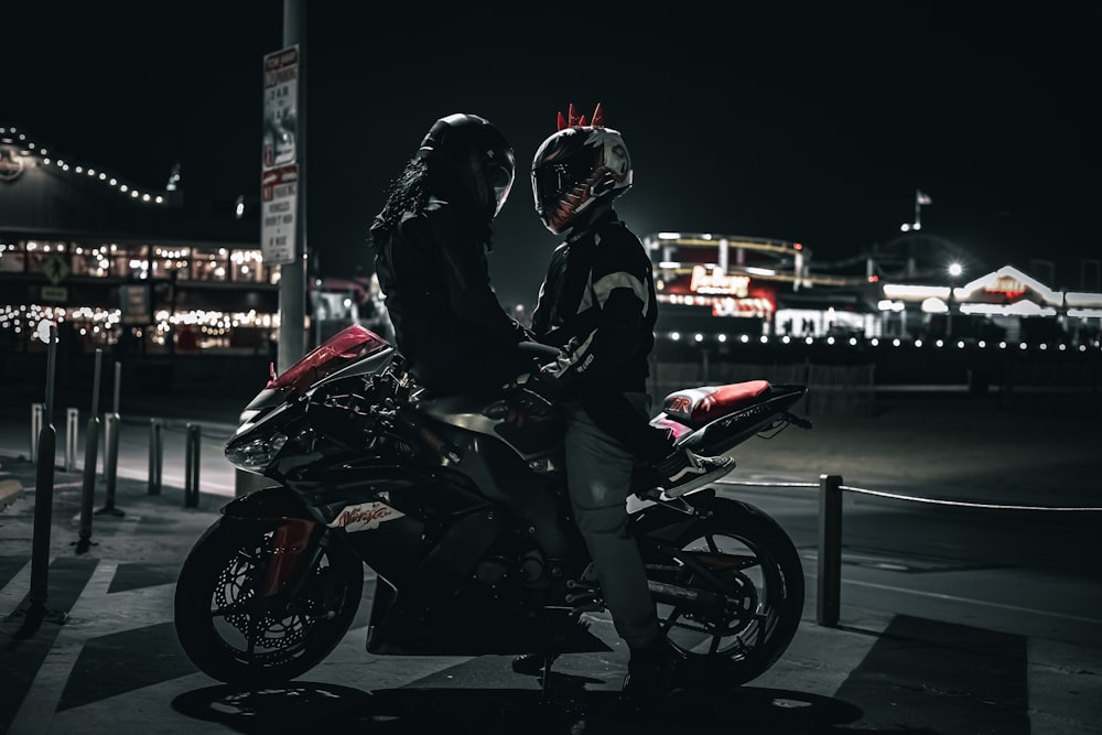 two people sitting on a motorcycle at night