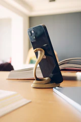 A flexible 'lazy' stand wrapped around a bedpost holding a phone for hands-free viewing.