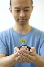 a man holding a small plant in his hands