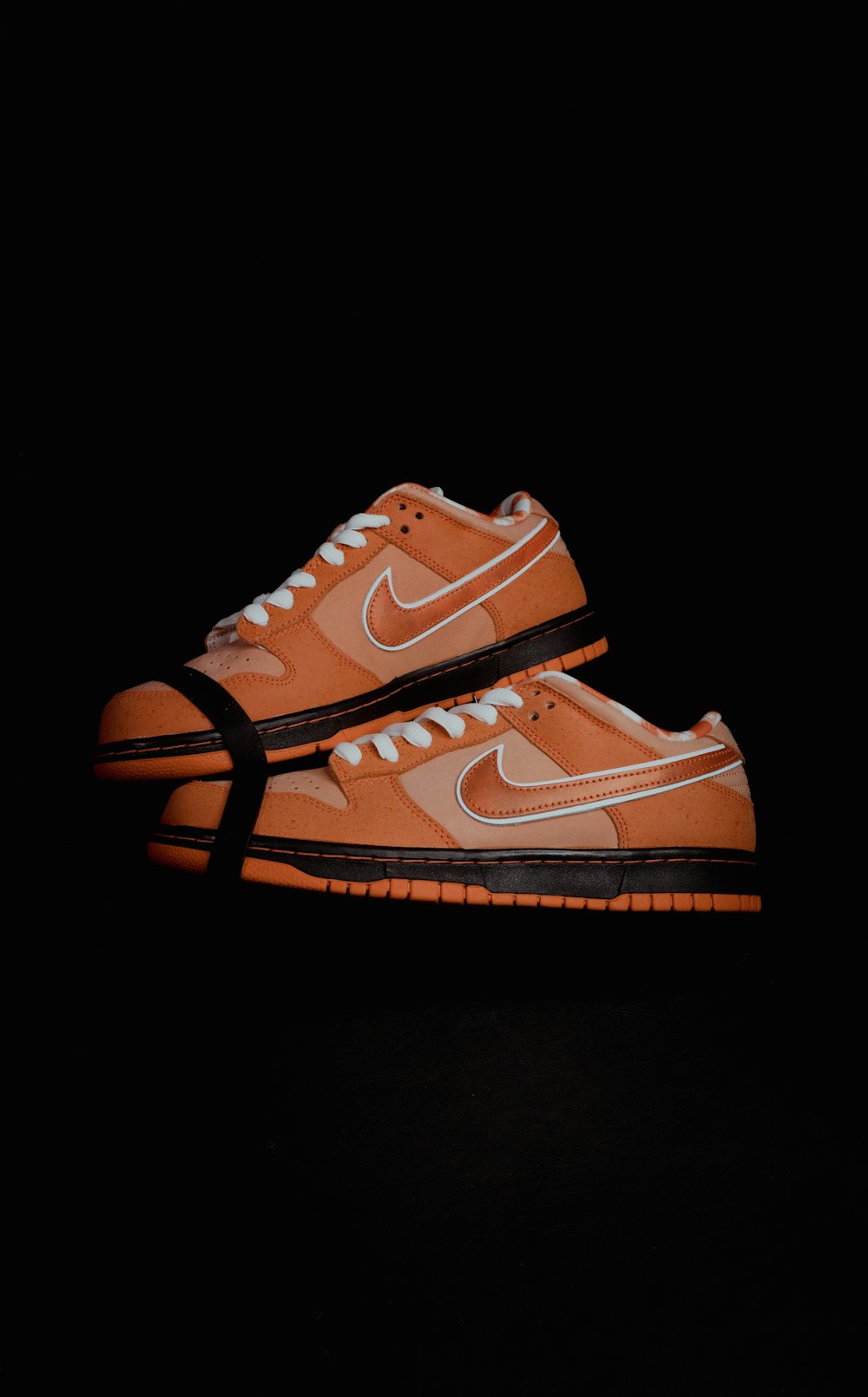 a pair of orange sneakers on a black background