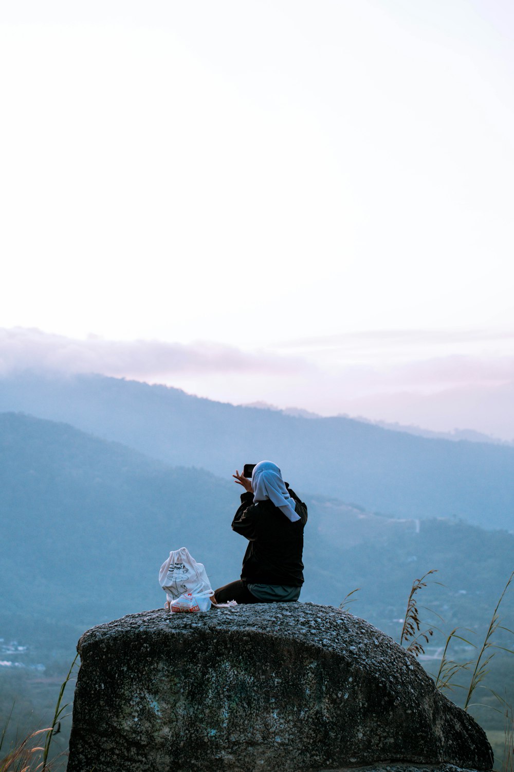 a person sitting on a rock taking a picture