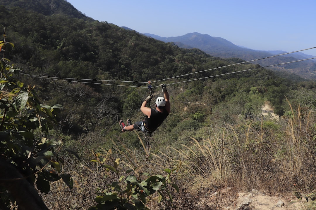 a man is zipping through the air on a rope, Muscular adult male zipline in Mexico