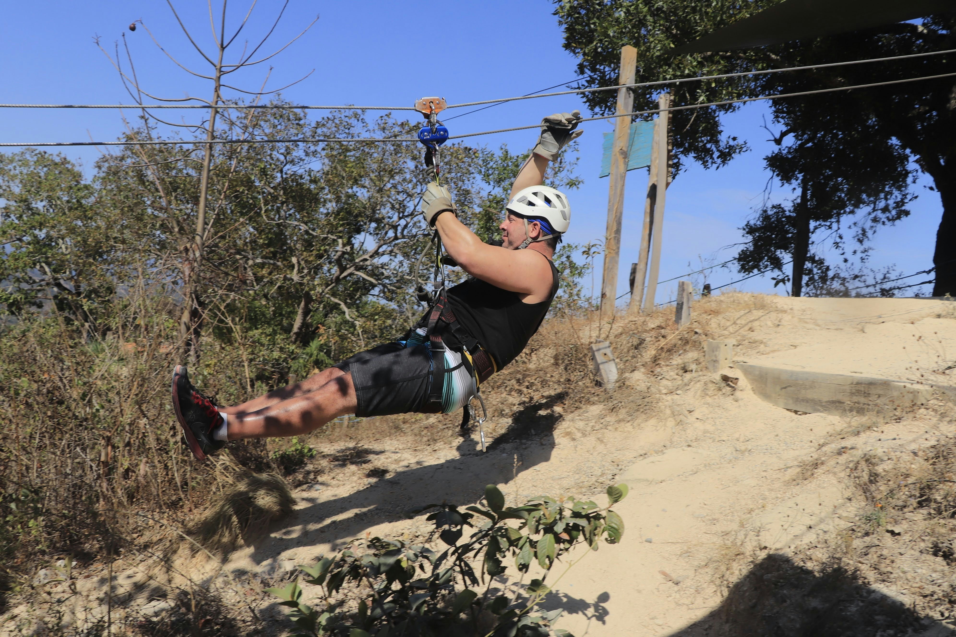 a man is zipping through the air on a rope, Muscular Man zip lining in Mexico
